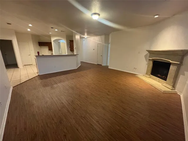 an empty room with wooden floor and a kitchen