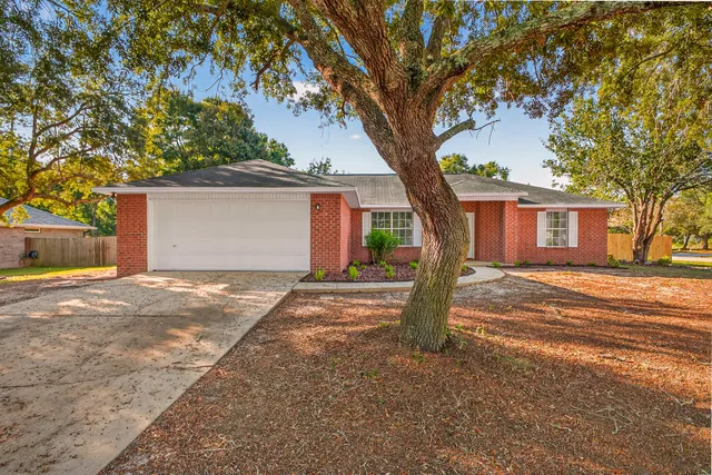 a front view of a house with yard and tree