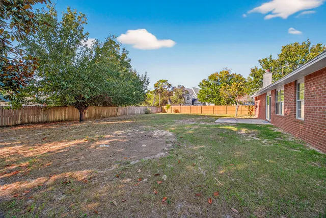 a view of a yard in front of a house with a large tree
