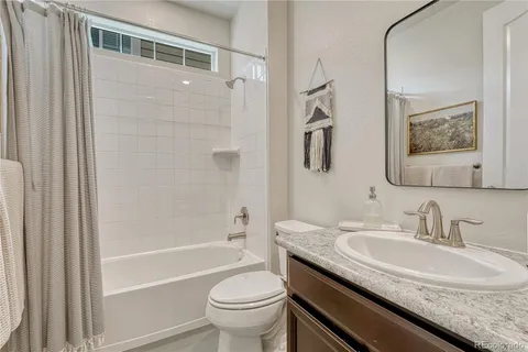a bathroom with a granite countertop sink a toilet and shower