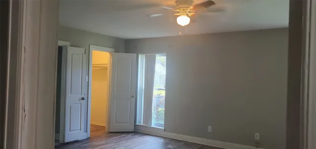 a view of an empty room with window and wooden floor