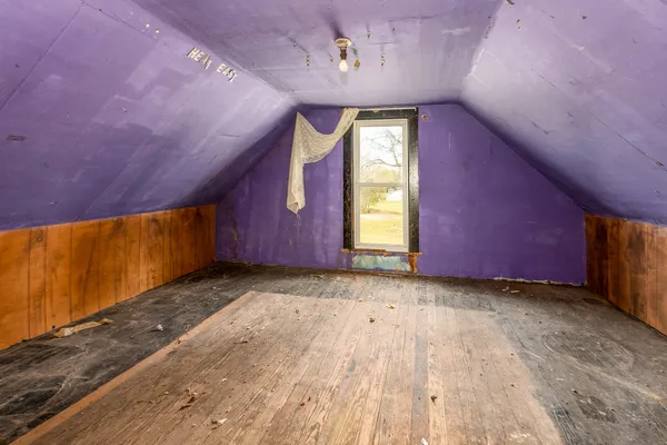 a view of an empty room with wooden walls and stairs