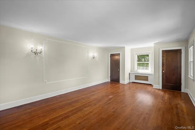 an empty room with wooden floor and window
