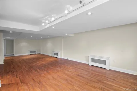 a view of an empty room with wooden floor and a ceiling fan