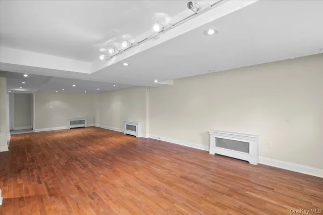a view of an empty room with wooden floor and a ceiling fan