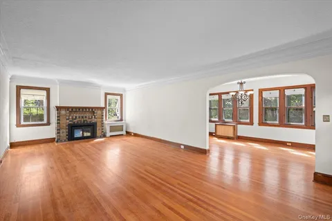 a view of an empty room with wooden floor fireplace and a window