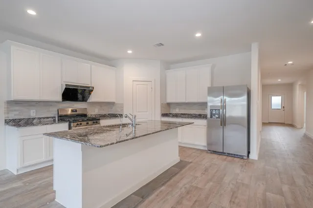 a kitchen with stainless steel appliances granite countertop a stove a sink and a refrigerator