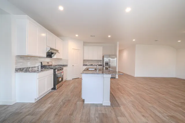 a kitchen with a sink wooden floor stainless steel appliances and cabinets