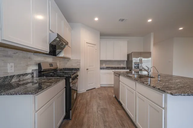 a kitchen with stainless steel appliances granite countertop a sink stove and cabinets