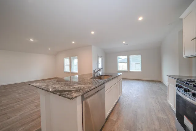 a kitchen with granite countertop sink stove and cabinets