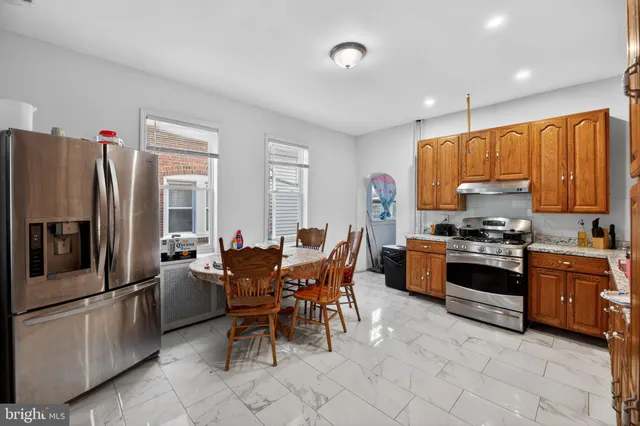 a kitchen with stainless steel appliances granite countertop a stove top oven a sink dishwasher a dining table and chairs with wooden floor