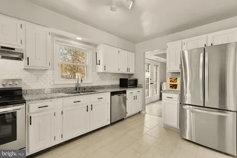 a kitchen with granite countertop white cabinets and refrigerator