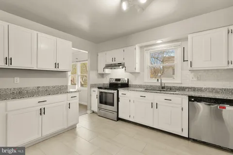 a kitchen with granite countertop white cabinets sink and stainless steel appliances