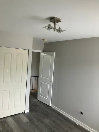an empty room with wooden floor cabinet and ceiling fan