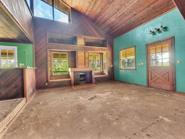 an empty room with windows and fireplace