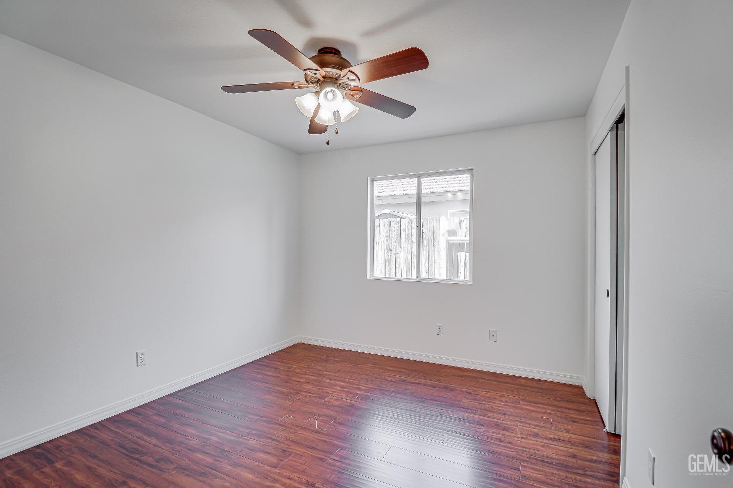 Undisclosed Address Bakersfield, CA 93312 - Photo 13 of 24 an empty room with wooden floor chandelier fan and windows
