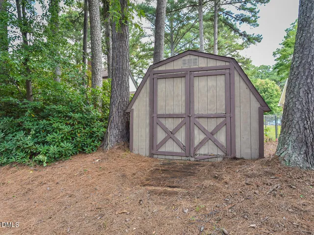 a view of backyard with a barn and large trees