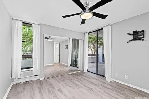 an empty room with wooden floor chandelier and windows
