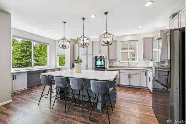 a kitchen with stainless steel appliances granite countertop a stove a refrigerator a kitchen island a table and chairs