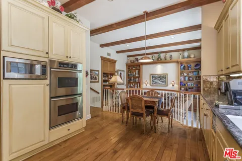 a open kitchen with stainless steel appliances granite countertop a stove top oven a dining table and chairs with wooden floor