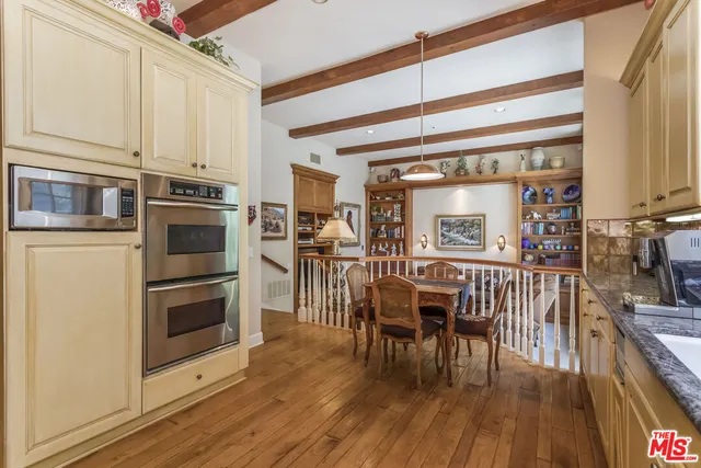 a open kitchen with stainless steel appliances granite countertop a stove top oven a dining table and chairs with wooden floor