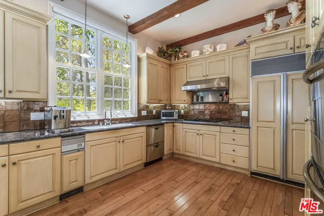 a kitchen with stainless steel appliances granite countertop a stove a sink and white cabinets with wooden floor