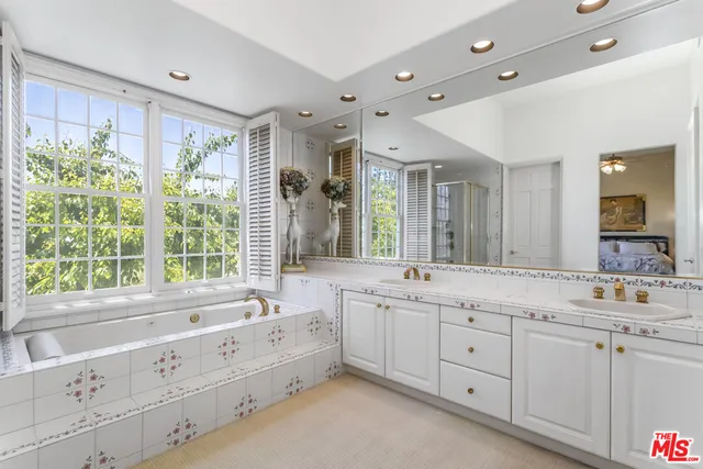 a spacious bathroom with double vanity a window a double vanity and a bathtub