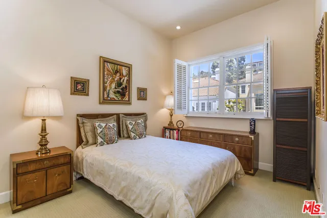 a bedroom with a bed and a lamp on dresser