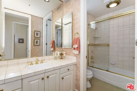 a bathroom with a double vanity sink toilet mirror and shower