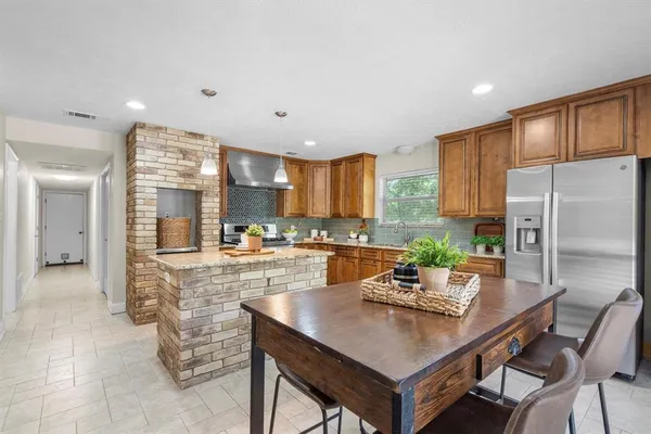 a kitchen with granite countertop a refrigerator a stove a sink a dining table and chairs