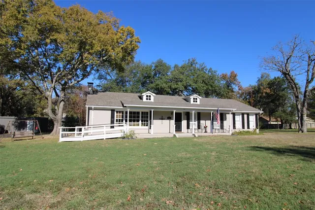a front view of a house with a garden and trees
