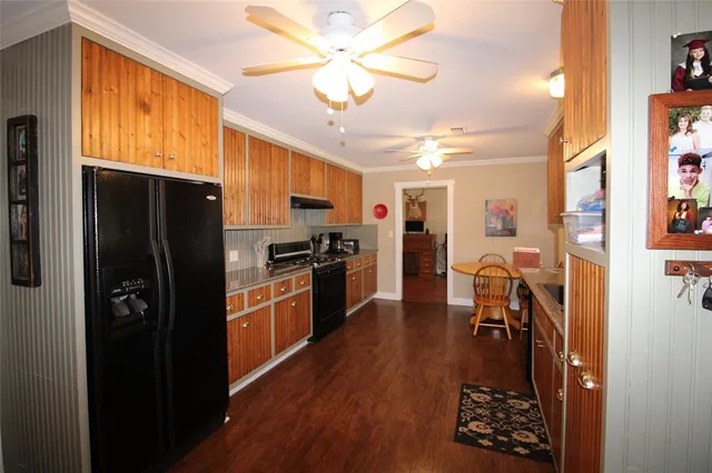 a kitchen with stainless steel appliances a refrigerator a stove a sink dishwasher a dining table and chairs with wooden floor