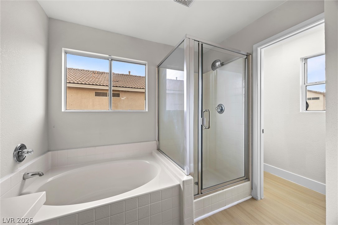 2650 Whisper Ridge Street Las Vegas, NV 89156 - Photo 17 of 28 A glass-enclosed shower stands alongside a deep soaking tub beneath a large window.