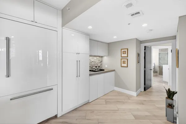 a kitchen with white cabinets and refrigerator