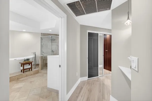 a view of a hallway with wooden floor and a bathroom