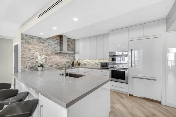 a kitchen with a refrigerator a stove a sink and white cabinets with wooden floor