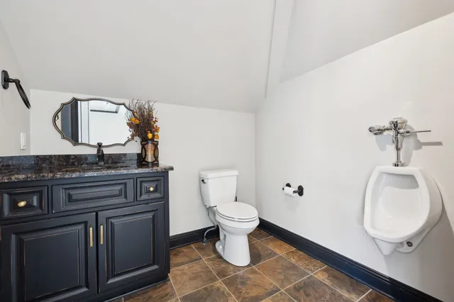 a bathroom with a granite countertop sink a toilet and a large mirror