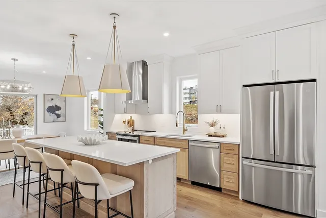 a kitchen with stainless steel appliances granite countertop a sink a stove a refrigerator and island with wooden floor