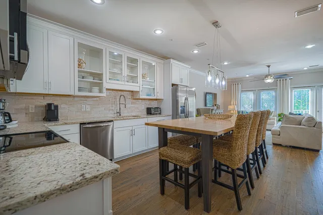 a kitchen with stainless steel appliances granite countertop wooden floor sink table and chairs