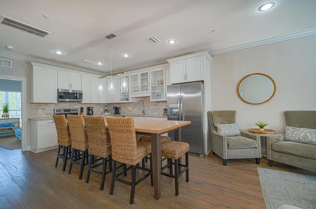 a kitchen with stainless steel appliances granite countertop a dining table chairs refrigerator sink and cabinets