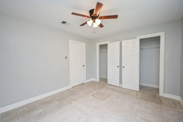 a view of an empty room with window and chandelier fan