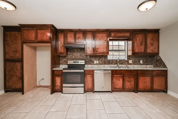 a large kitchen with stainless steel appliances granite countertop a refrigerator and a stove top oven