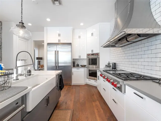 a kitchen with stove a sink and white cabinets with wooden floor
