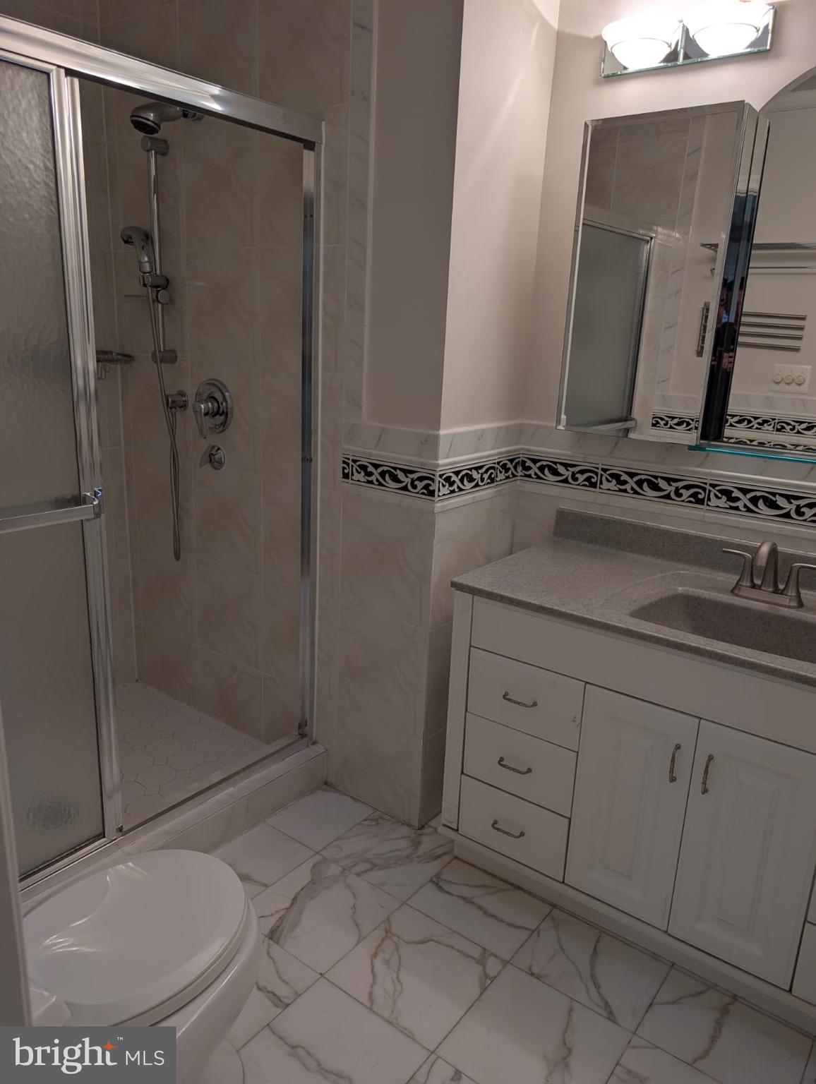 6705 Goldsboro Road Bethesda, MD 20817 - Photo 34 of 60 a bathroom with a granite countertop sink a mirror and shower