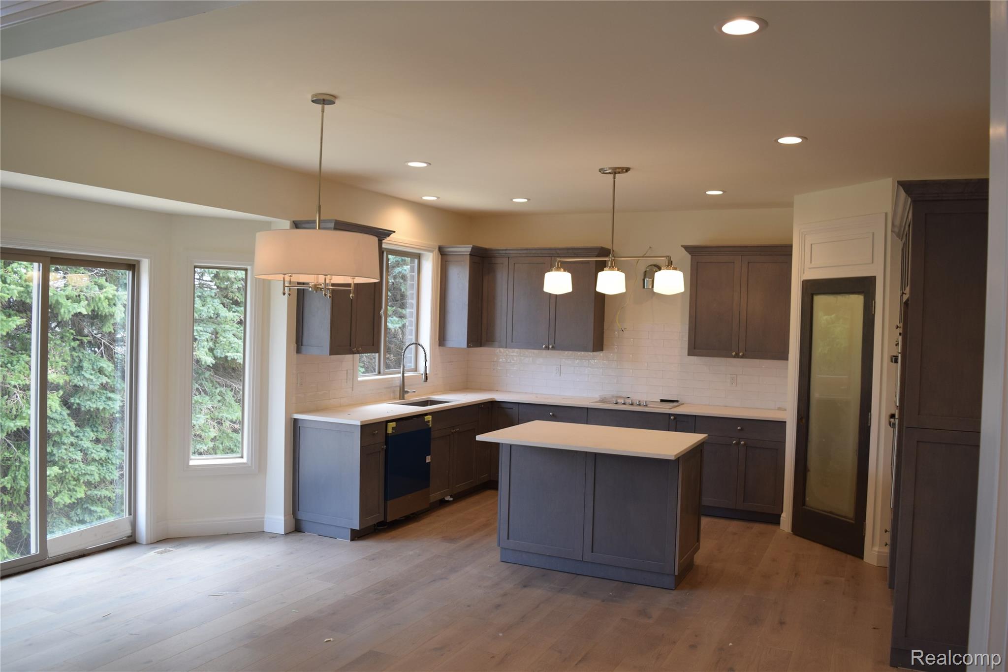 3093 Raffler Drive Rochester, MI 48307 - Photo 19 of 34 Kitchen featuring hanging light fixtures, a kitchen island, light wood floors, decorative backsplash, and recessed lighting