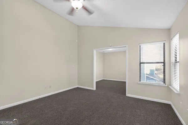an empty room with windows and chandelier fan
