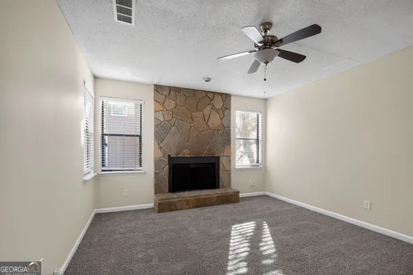an empty room with windows and fireplace