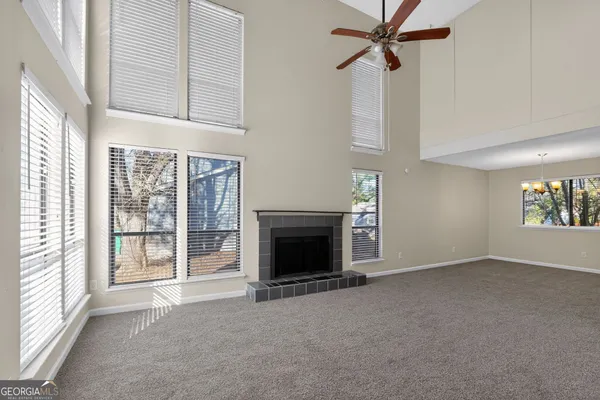 an empty room with windows fireplace and fans
