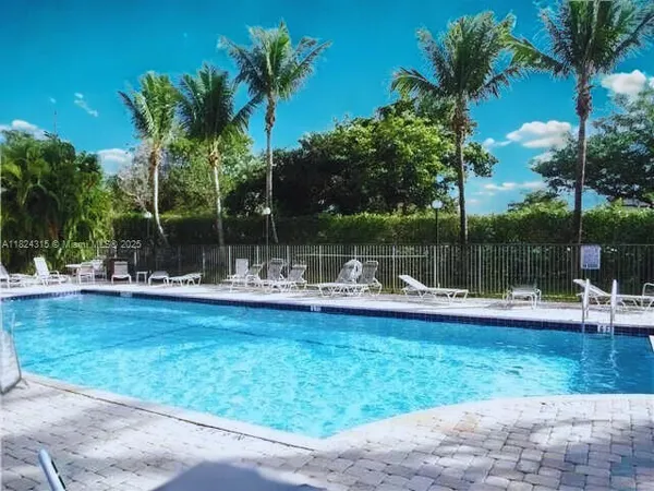 a view of swimming pool with lawn chairs and plants