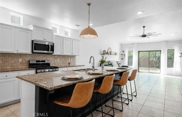 a kitchen with stainless steel appliances granite countertop a stove a sink a microwave a dining table and chairs